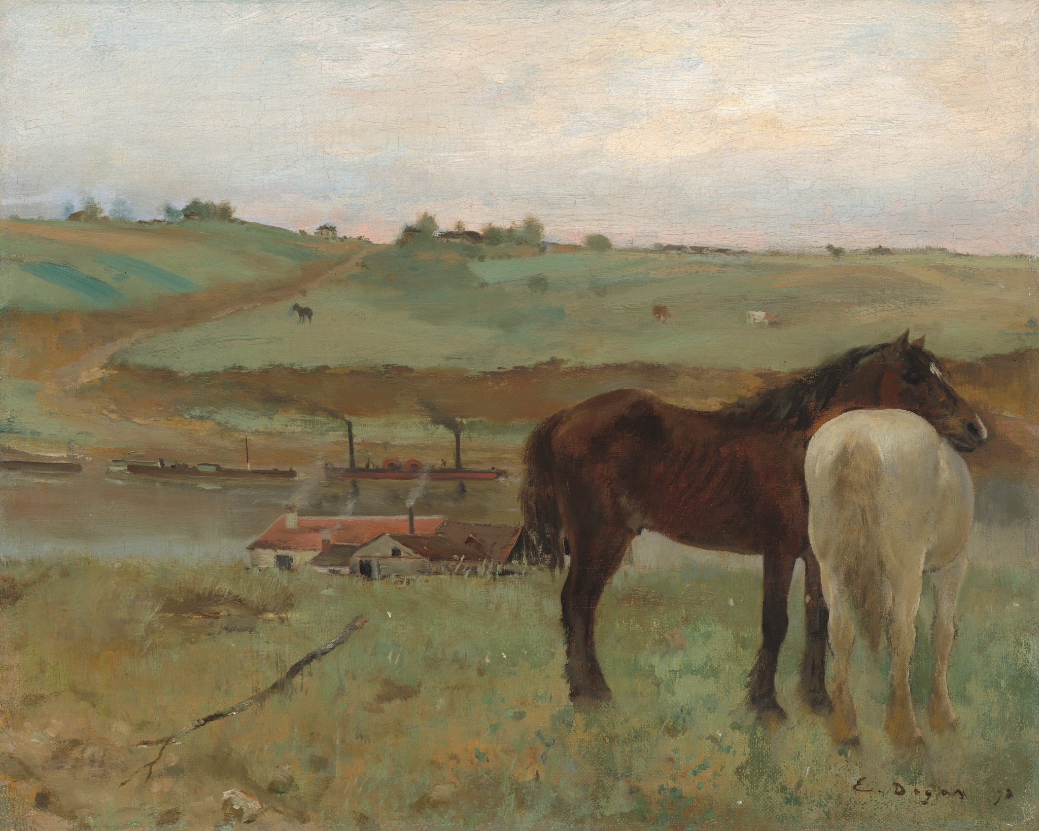 Two horses standing in a meadow above a river
